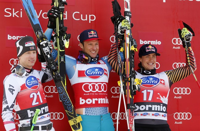 Norway's Aksel Lund Svindal, center, winner of an alpine ski men's World Cup downhill, celebrates on the podium with second-placed Austria's Hannes Reichelt, left, and third-placed Canada's Erik Guay, in Bormio, Italy, Sunday, Dec. 29, 2013. (AP Photo/Alessandro Trovati).