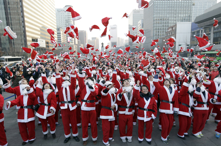 More than 1,000 volunteers clad in Santa Claus costumes throw their hats in the air as they gather to deliver gifts for the poor in downtown Seoul, South Korea, Tuesday, Dec. 24, 2013.