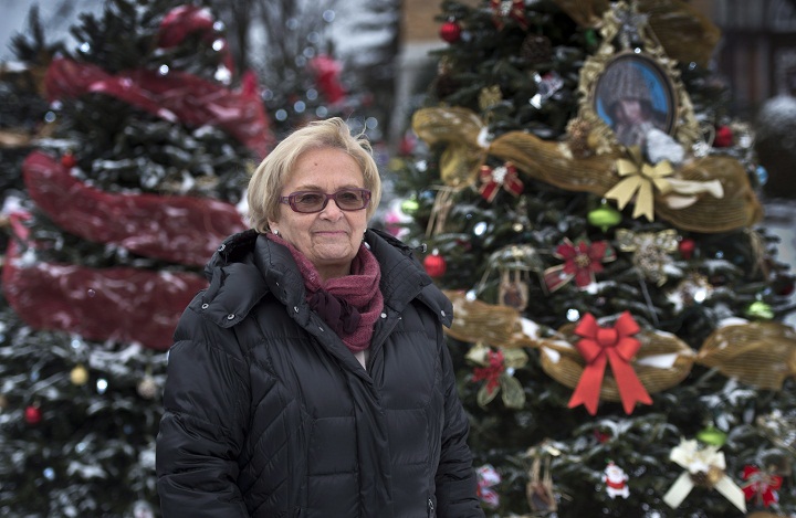 Mayor Colette Roy-Laroche stands next to Christmas trees placed in front of the church Sunday, December 8, 2013 in Lac-Megantic, Que., one for every one of the 47 victims of an oil tanker train derailment that burned the most part of downtown Lac-Megantic in July.