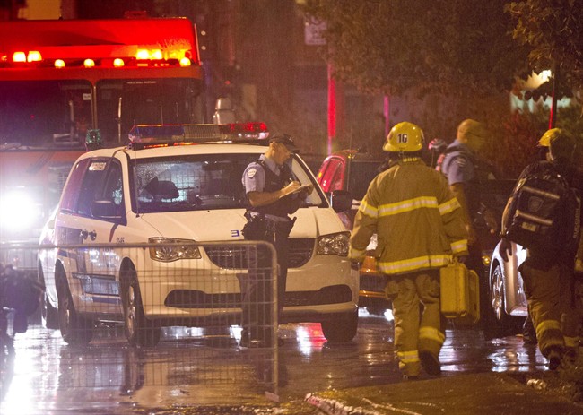 Police and firefighters work at the rear of an auditorium where a gunman shot and killed at least one person during the PQ victory rally on September 5, 2012, in Montreal. 