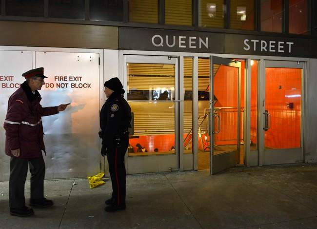 A TTC employee talks with a police officer at the Queen Street subway station entrance in Toronto on Friday Dec. 13, 2013.