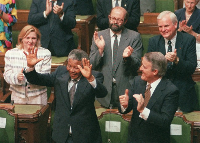 South African anti-apartheid activist Nelson Mandela raises his arms as he is acknowledged by the Prime Minister Brian Mulroney and other members of Parliament in Ottawa, June 18, 1990. THE CANADIAN PRESS/Fred Chartrand.