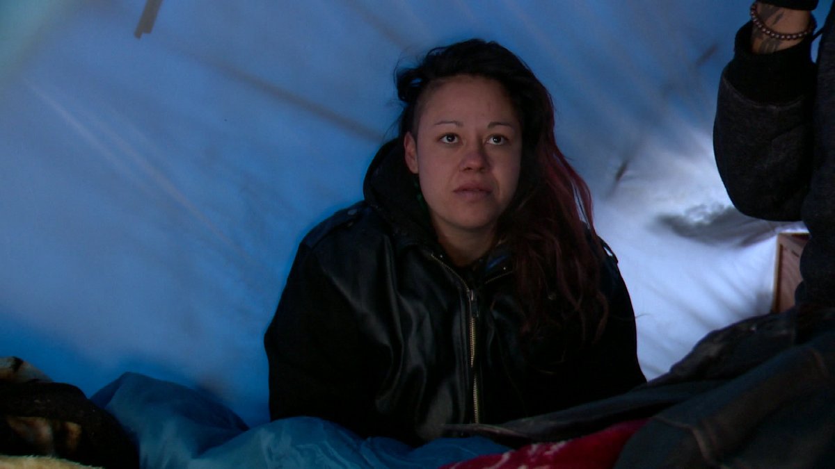 A woman takes shelter from the cold in a tent in a makeshift camp in the Manchester Industrial area.