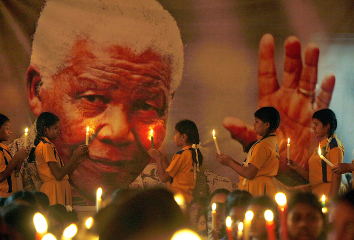 Schoolchildren hold candles near a giant portrait of former South African President Nelson Mandela in Chennai, India, Friday, Dec. 6, 2013.