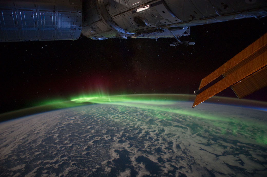 The ISS soars above Earth while the southern lights dance.