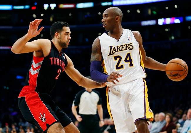 Los Angeles Lakers' Kobe Bryant dribbles the ball as he is guarded by Toronto Raptors' Landry Fields, left, during the first quarter of an NBA basketball game in Los Angeles, Sunday, Dec. 8, 2013.