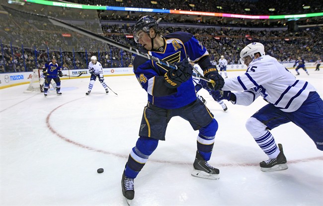 St. Louis Blues' T.J. Oshie, left, tries to keep his eye on a loose puck along side Toronto Maple Leafs' Paul Ranger, right, during the second period of an NHL hockey game Thursday, Dec. 12, 2013, in St. Louis. (AP Photo/Jeff Roberson).