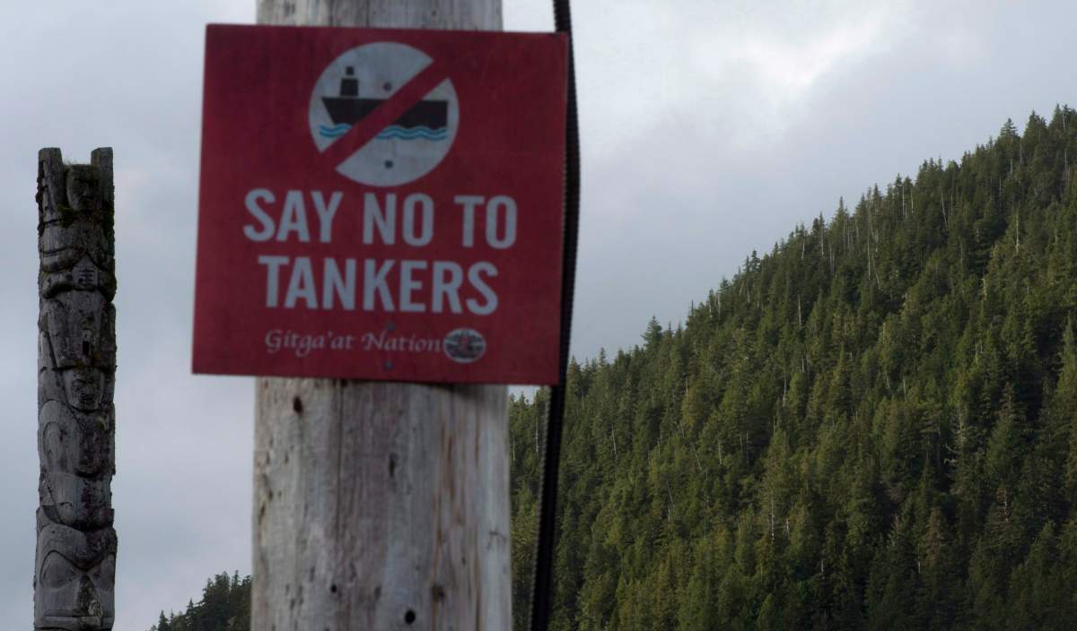 An anti-tanker sign is seen with an ancient totem pole in the background in Hartley Bay, B.C. Tuesday, Sept, 17, 2013. 