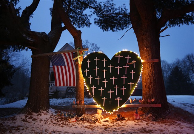  In this Saturday, Dec. 14, 2013, file photo, a makeshift memorial with crosses for the victims of the Sandy Hook massacre stands outside a home in Newtown, Conn., the one-year anniversary of the shootings. 