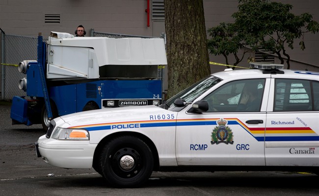 A rink attendant dumps snow from a Zamboni as an RCMP officer sits outside the Newton Arena in Surrey, B.C., on Monday December 30, 2013, where a 53-year old woman was attacked outside the arena Sunday night. The RCMP Integrated Homicide Investigation Team said the woman is not expected to survive. THE CANADIAN PRESS/Darryl Dyck.
