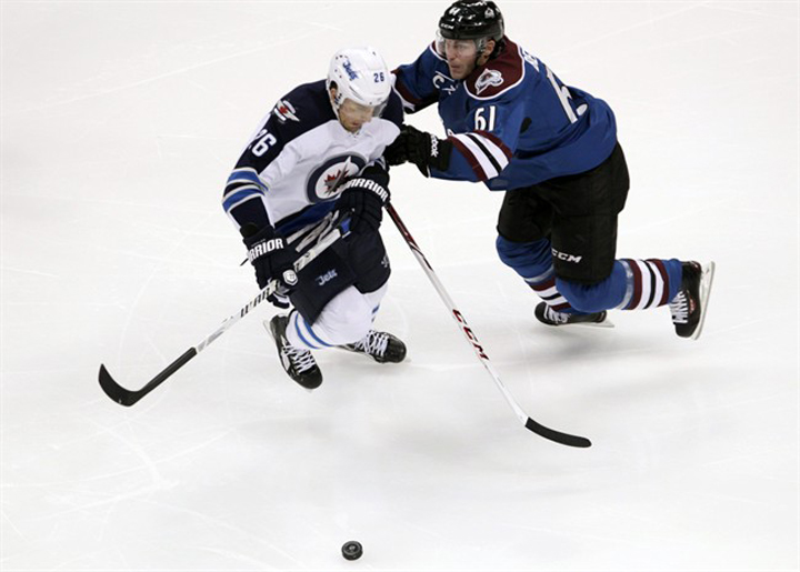 Colorado Avalanche defenceman Andre Benoit (61) pushes Winnipeg Jets right wing Blake Wheeler away from the puck during the first period in Denver on Sunday.