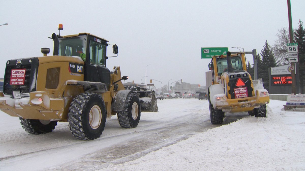Crews work to clear piles of snow along Portage Avenue on Saturday.