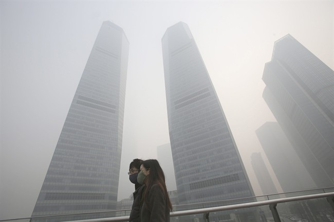 A couple in protective masks walk under haze in Shanghai, China, Friday, Dec. 6, 2013.