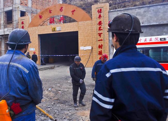 In this Friday, Dec. 13, 2013 photo released by China's Xinhua News Agency, miners wait at the entrance to the Baiyanggou coal mine after a gas explosion occurred, in Xinjiang region's Changji prefecture, western China.
