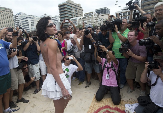 A woman poses for photos during a protest against a topless ban on the Ipanema beach, in Rio de Janeiro, Brazil, Saturday, Dec. 21, 2013. 