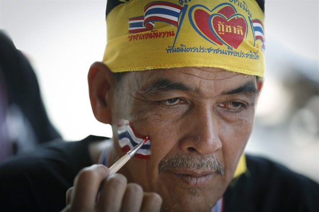 An anti-government protester draws a Thai national flag on the face of another protester at Democracy Monument in Bangkok, Thailand, Sunday, Dec. 8, 2013. 