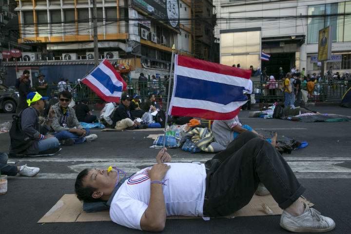 An anti-government protester rests on the street of a major intersection in downtown Bangkok