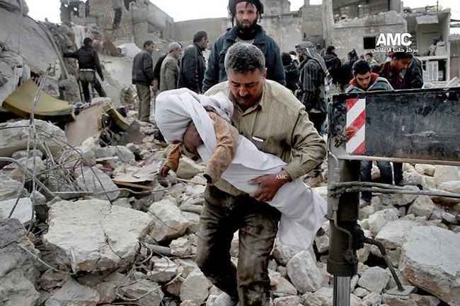 In this Wednesday, Jan. 29, 2014 citizen journalism image provided by Aleppo Media Center shows a Syrian man carrying the body of a child who was killed following a Syrian government airstrike in Aleppo, Syria. 