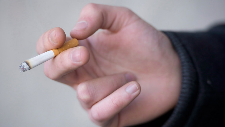 A smoker is seen holding his cigarette during a smoke break outside a building in North Vancouver, B.C. Monday, Jan. 20, 2014. The Saskatchewan government is offering an innovative school initiative program during national non-smoking week in the province.