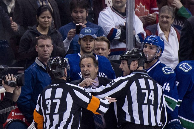 Referees get in the way of Vancouver Canucks head coach John Tortorella as he screams at the Calgary Flames bench during first period NHL hockey action at Rogers Arena in Vancouver, B.C. Saturday, January 18, 2014. Tortorella has been suspended for 15 days following his actions in Saturday's fight-filled game with the Calgary Flames.