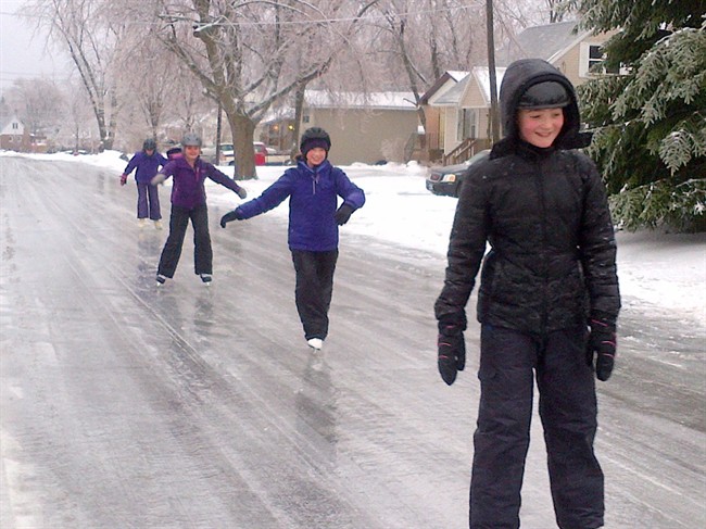 Kids skate on an ice-covered street in Kingston, Ont., on Saturday, December 21, 2013