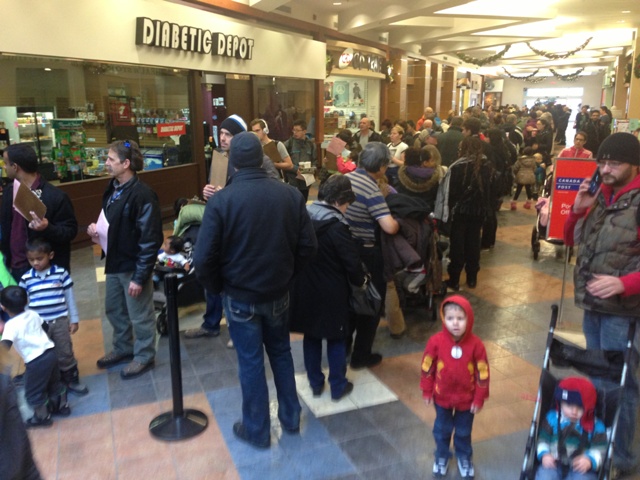 Dozens of people wait in line for a flu shot at the Brentwood Village Mall clinic on Tuesday, January 7.