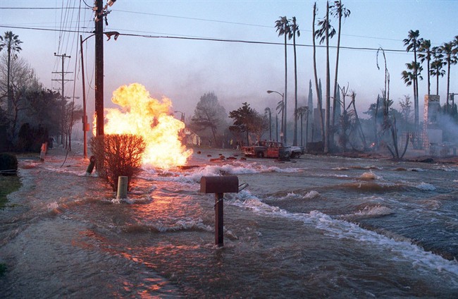 In this Jan. 17, 1994 file photo, gas from a ruptured supply line burns as water from broken water main floods Balboa Boulevard in the Granada Hills area of Los Angeles.  