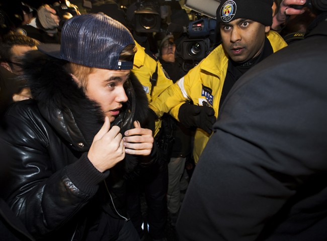 Canadian musician Justin Bieber is swarmed by media and police officers as he turns himself into city police in Toronto on Wednesday, January 29, 2014. 