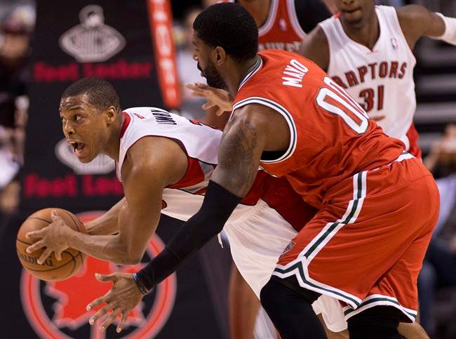 Toronto Raptors guard Kyle Lowry, left, battles for the ball against Milwaukee Bucks guard O.J. Mayo during first half NBA basketball action in Toronto on Monday, January 13, 2014. 