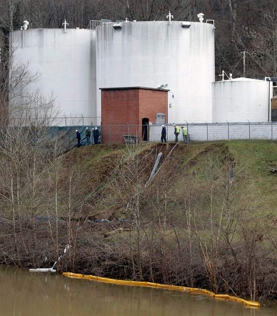 In this Monday, Jan. 13, 2014, file photo, workers inspect an area outside a retaining wall around storage tanks where a chemical leaked into the Elk River at Freedom Industries storage facility in Charleston, W.Va.