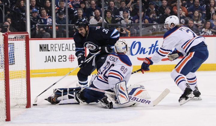 Dustin Byfuglien #33 of the Winnipeg Jets tries to get the puck past Ilya Bryzgalov #80 of the Edmonton Oilers in second period action in an NHL game at the MTS Centre on January 18, 2014 in Winnipeg, Manitoba.