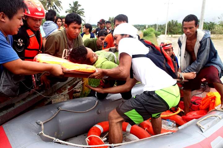 In this Sunday, Jan. 12, 2014 photo, rescuers from the Comval Emergency Response Team evacuate residents who were trapped in flooding of Compostela Valley and nearby provinces in southern Philippines. (Photo credit: AP Photo)