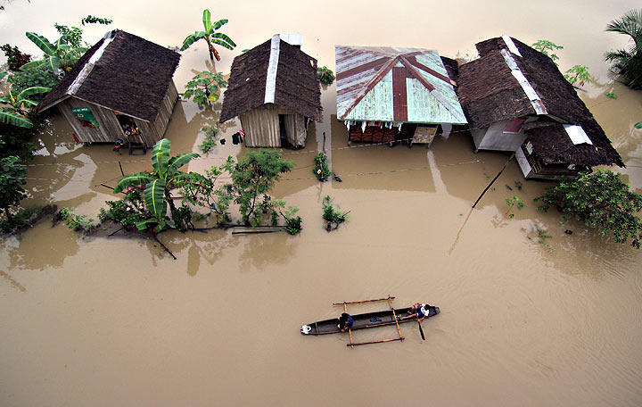 Philippines flooding: Residents ride a wooden boat as they paddle past submerged houses due to flooding brought about by heavy rains in the outskirts of Butuan City, Agusan del sur province, in southern island of Mindanao on January 13, 2014. Twenty-two people have been killed and nearly 200,000 others evacuated from floods and landslides that hit a southern Philippine region still recovering from a deadly 2012 typhoon, the government said January 14.