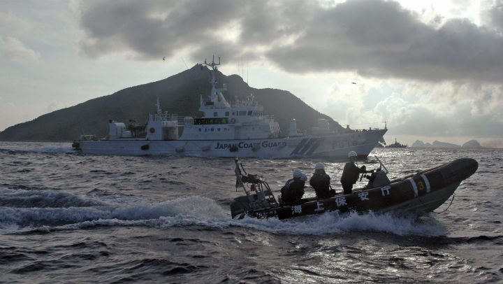 Japanese Coast Guard boat and vessel sail alongside Japanese activists' fishing boat, not in photo, warning the activists away from a group of disputed islands called Diaoyu by China and Senkaku by Japan, early Sunday, Aug. 18, 2013.  (File photo).