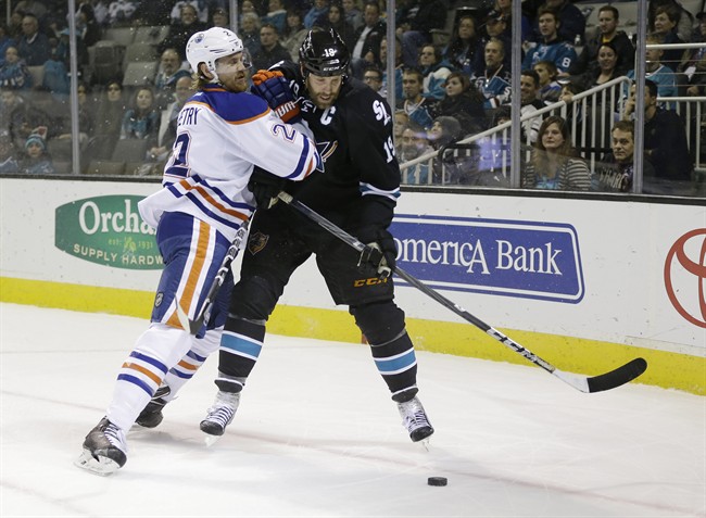 Edmonton Oilers' Jeff Petry, left, battles against San Jose Sharks' Joe Thornton during the first period of an NHL hockey game Thursday, Jan. 2, 2014, in San Jose, Calif. 