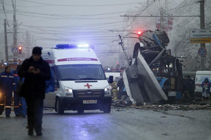 In this Monday, Dec. 30, 2013 file photo an ambulance leaves the site of an explosion after a bomb blast tore through a bus, background, in the city of Volgograd. 