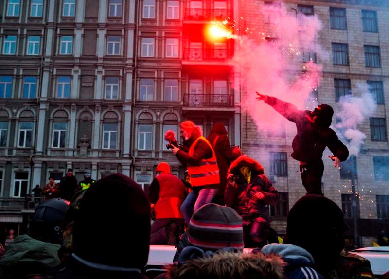 A protester throws a burning flare during clashes with police, in central Kyiv, Ukraine, Sunday, Jan. 19, 2014. (AP Photo/Evgeny Feldman).