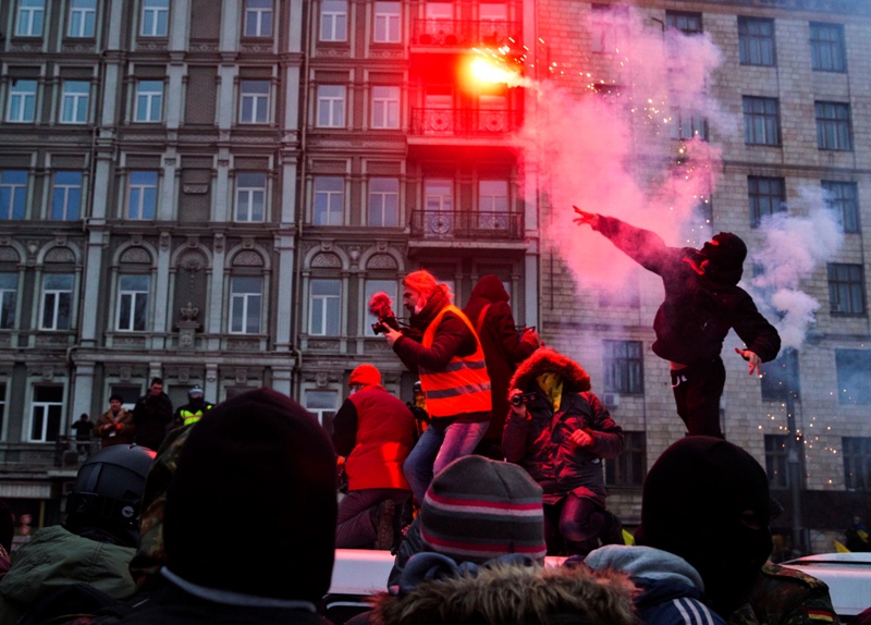 A protester throws a burning flare during clashes with police, in central Kyiv, Ukraine, Sunday, Jan. 19, 2014. (AP Photo/Evgeny Feldman).