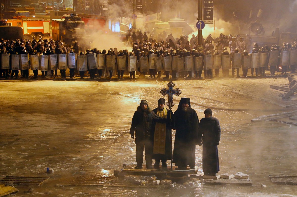 Orthodox priests pray as they stand between pro-European Union activists and police lines in central Kiev, Ukraine, early Friday, Jan. 24, 2014. 