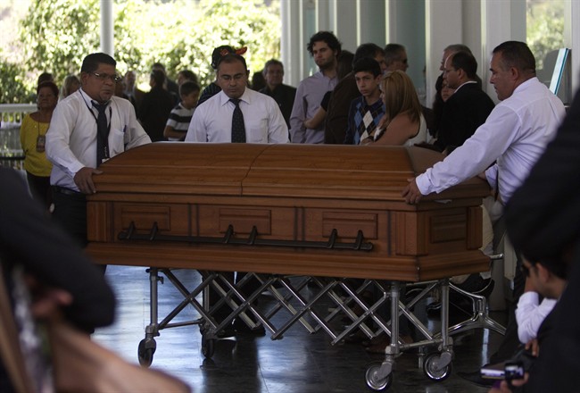 Funeral service workers push the coffin that contain the remains of Monica Spear, a popular soap-opera actress and former Miss Venezuela, into the East cemetery chapel in Caracas, Venezuela, Thursday, Jan. 9, 2014. 