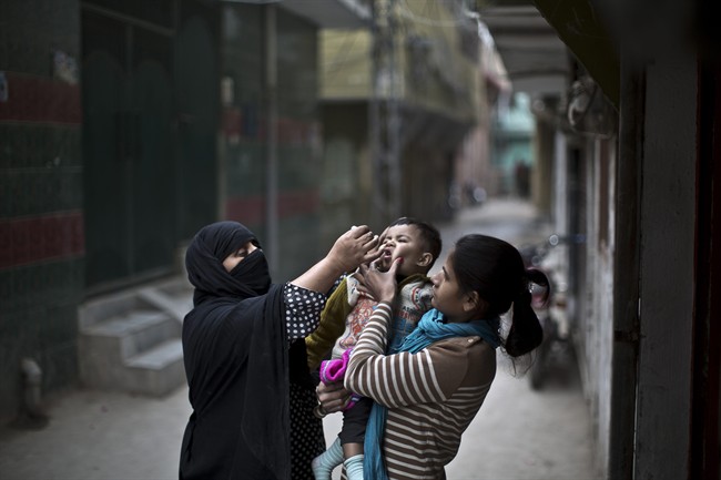 A Pakistani woman, right, holds her nephew to be vaccinated against polio by Mariam Jabir, 32, while going house to house checking on children who need the vaccine, in Rawalpindi, Pakistan.Two bombs minutes apart struck tribal police assigned to guard polio workers in northwest Pakistan on Saturday, killing 11, police said.