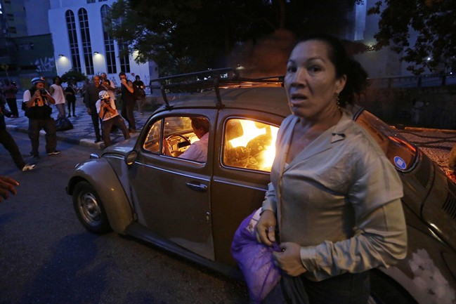  A man drives his car which caught fire when he tried to drive past a burning barricade set up by protesters who were demanding better public services and protesting against the upcoming World Cup soccer tournament in Sao Paulo, Brazil, Saturday, Jan. 25, 2014. 