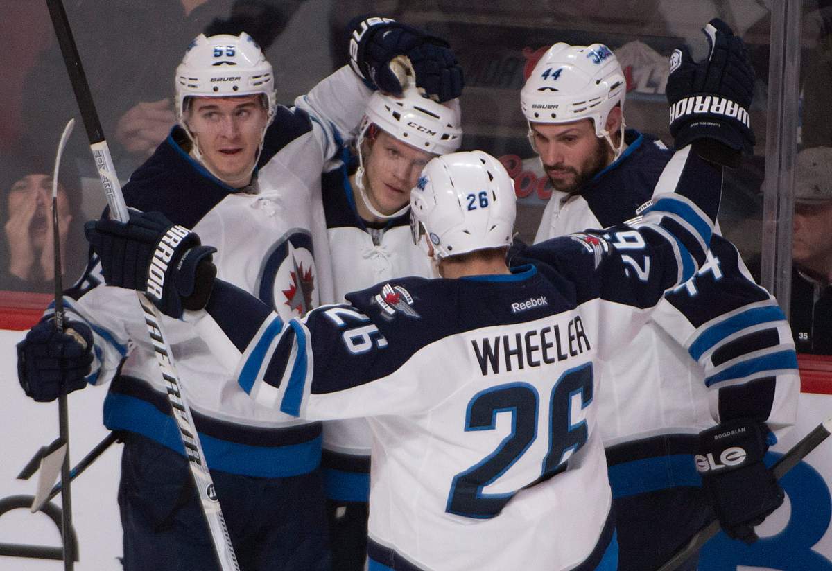 Winnipeg Jets' Tobias Enstrom, second from left, gets congratulated by teammates Mark Scheifele (55), Blake Wheeler (26) and Zach Bogosian (44)after scoring against the Montreal Canadiens during second period NHL action in Montreal on Sunday, February 2, 2014.