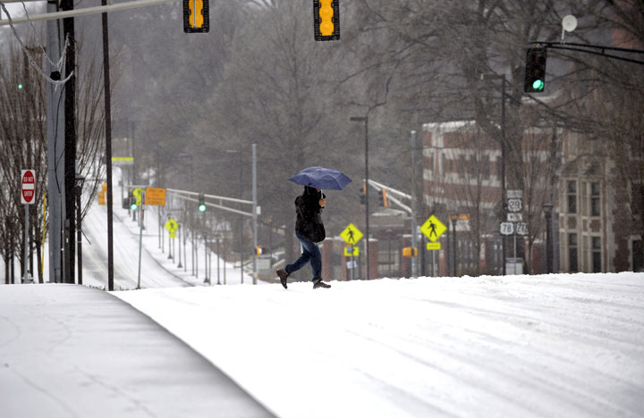 A pedestrian walks across downtown’s North Avenue during a winter storm on Wednesday, Feb. 12, 2014, in Atlanta.
