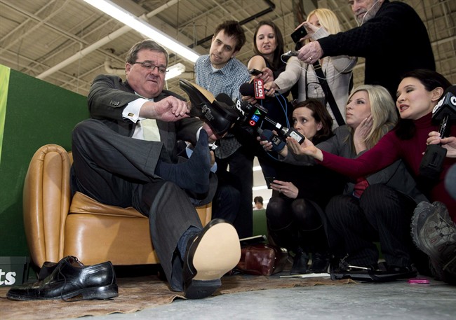 Finance Minister Jim Flaherty puts on his annual pre-budget shoes at the Roots Leather Factory in Toronto on Wednesday, March 20, 2013. 