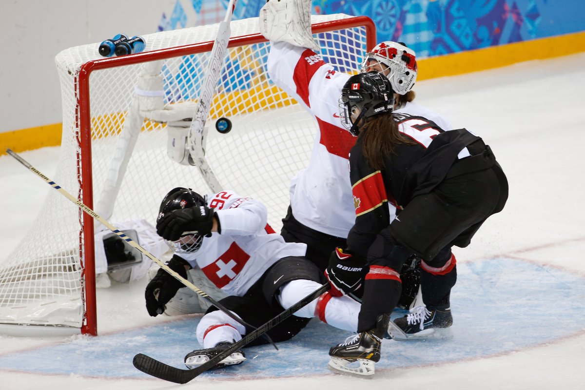 Rebecca Johnston of Canada watches her  shot sail into the net past Sandra Thalmann of Switzerland (92) and goalie Florence Schelling during the second period of the women's ice hockey game at the Shayba Arena during the 2014 Winter Olympics, Saturday, Feb. 8, 2014, in Sochi.