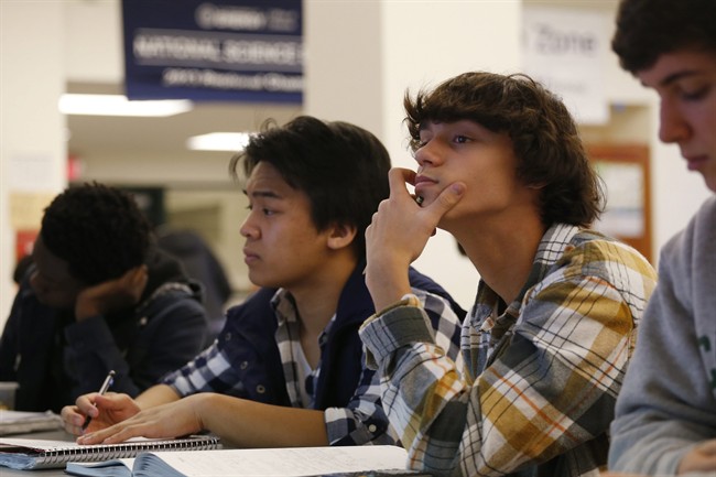 Students Julian Lopez, 12th grade, second left; Ben Montalbano, 11th grade, second right; and James Agostino, 12th grade, right; listen during their Advanced Placement (AP) Physics class at Woodrow Wilson High School.
