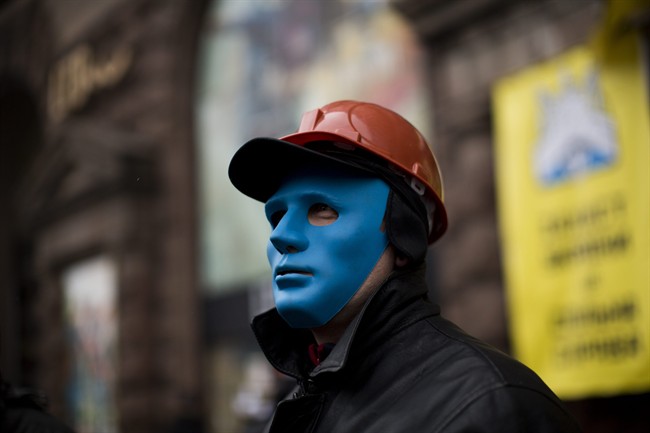 An anti-Yanukovych protester protects the entrance of a shop occupied by demonstrators still camped out on Kiev's Independence Square, the epicenter of the country's current unrest, Ukraine, Tuesday, Feb. 25, 2014. (AP Photo/Emilio Morenatti).