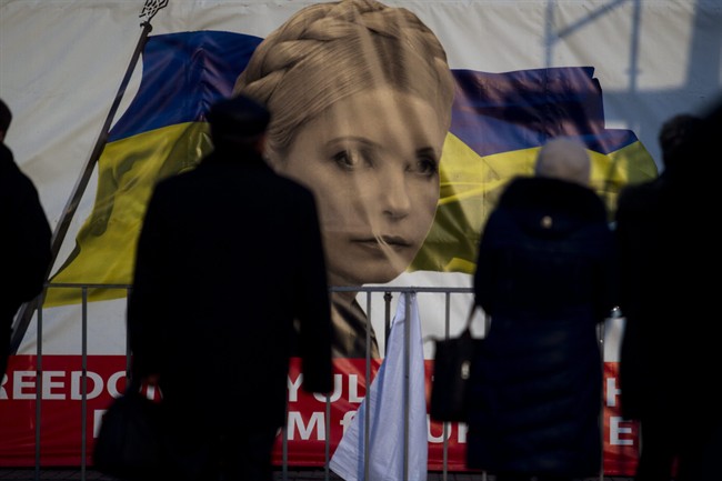 People pass by a portrait of Yulia Tymoshenko, a prominent opposition leader at Independence Square in Kiev, Ukraine, Monday, Feb. 24, 2014. 
