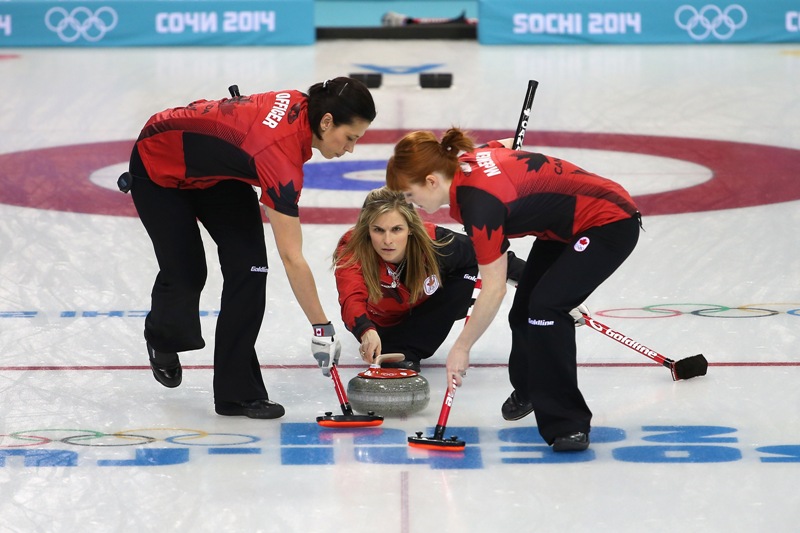 Jennifer Jones of Canada delivers the stone as Jill Officer and Dawn McEwen of Canada sweep the ice during Curling Women's Round Robin match between Canada and Japan on day eight of the Sochi 2014 Winter Olympics at Ice Cube Curling Center on February 15, 2014 in Sochi, . (Photo by Quinn Rooney/Getty Images).